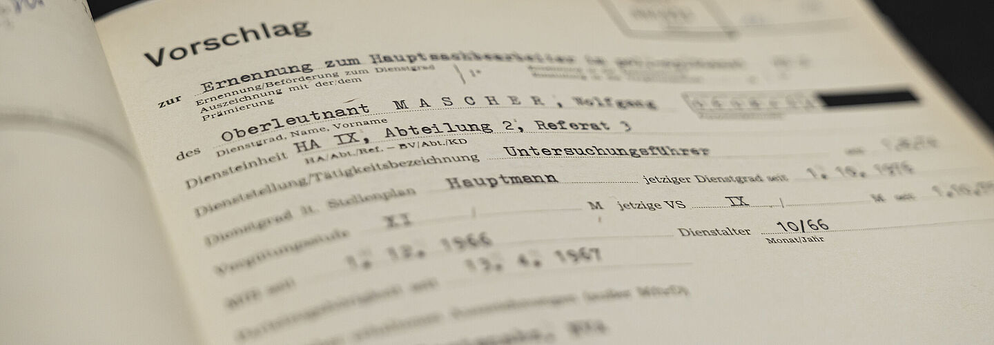 Blick in eine aufgeschlagene Beispielakte. Zu sehen sind Informationen zur Anstellung Wolfgang Maschers als Untersuchungsführer der Hauptabteilung IX der Stasi